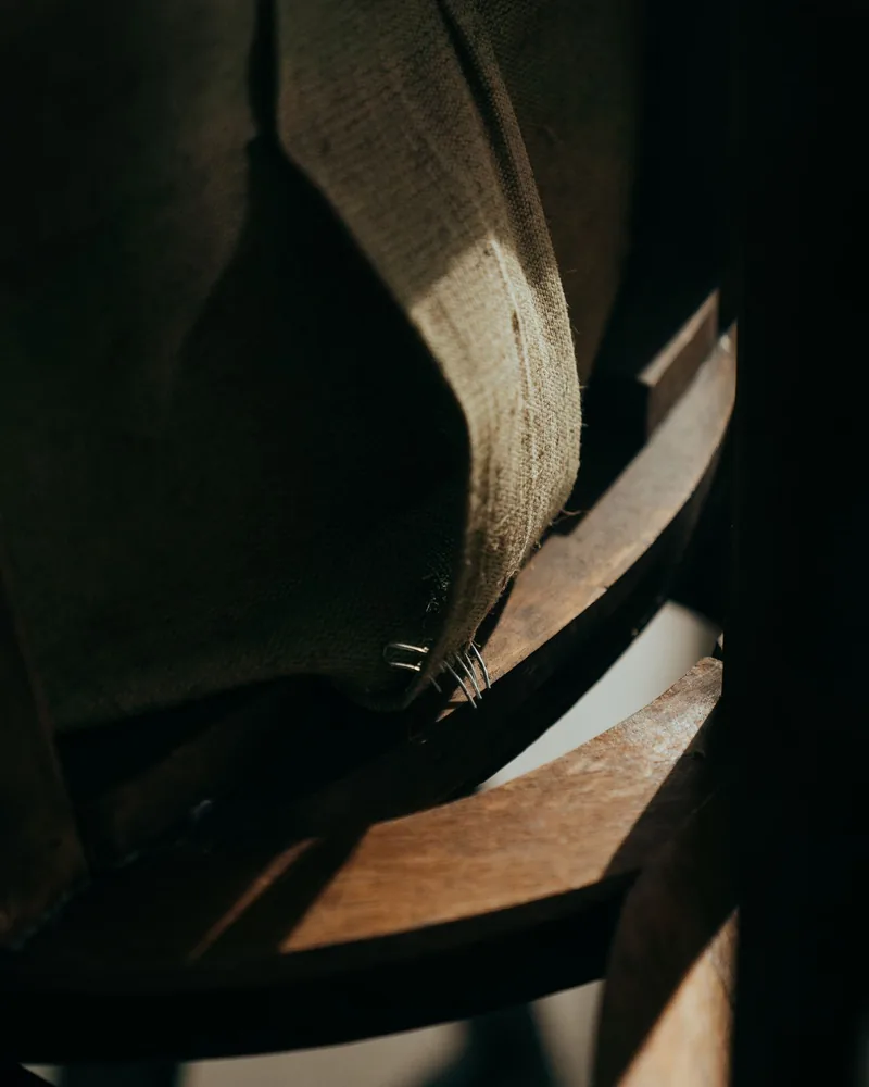 Detail jutové tkaniny připevněné skobami k dřevěnému rámu židle